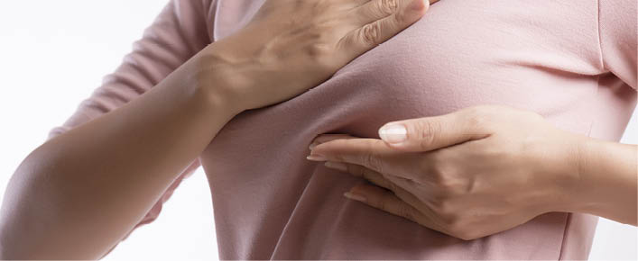 Woman hand checking lumps on her breast for signs of breast cancer on gray background  Healthcare concept 